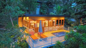 Une maison en bois dotée d’un balcon, entourée d’une végétation luxuriante.