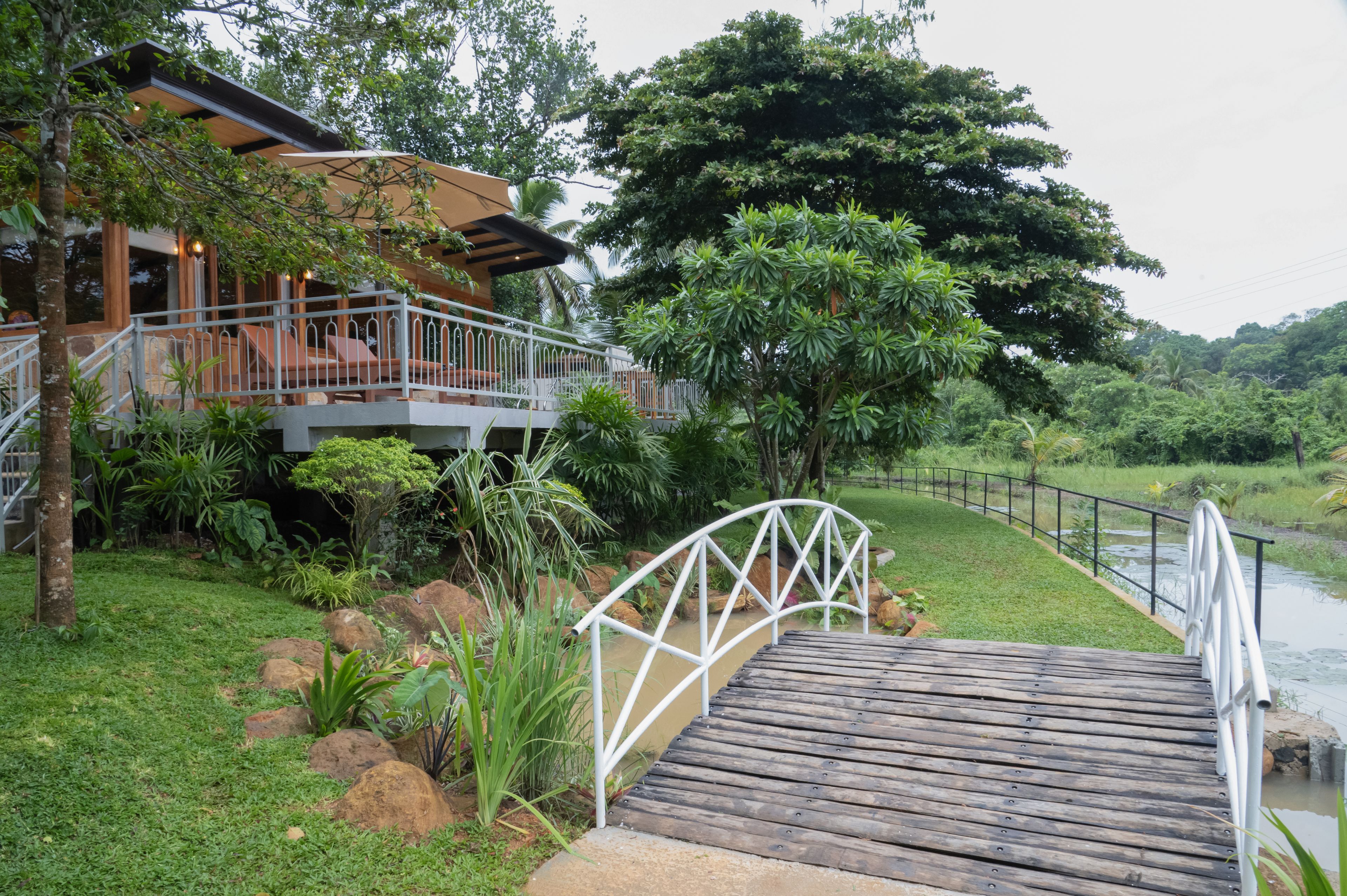Un puente de madera que conduce a una casa con balcón, con vistas a un río.