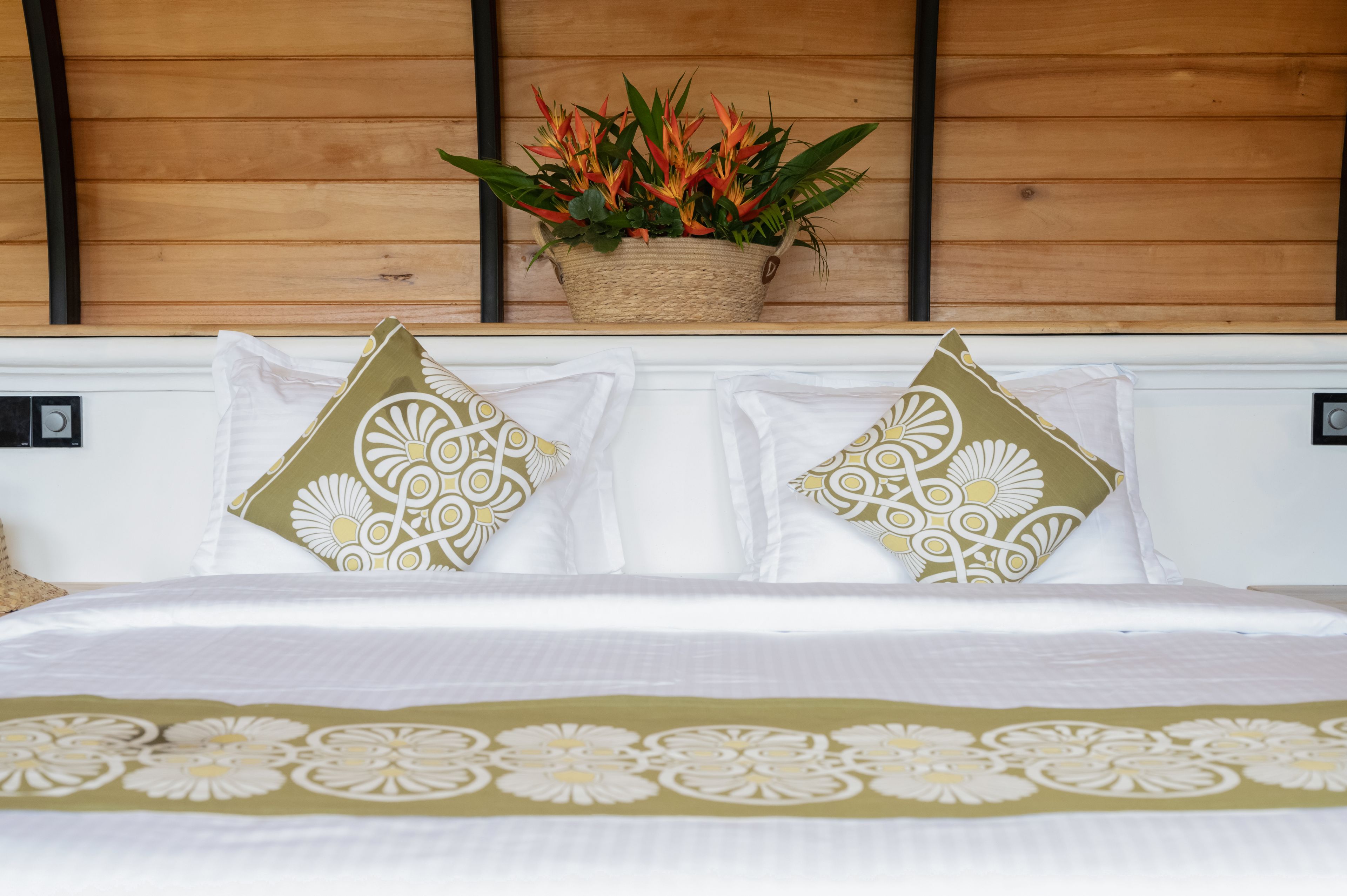 Una cama con ropa de cama blanca y dos almohadas decorativas con estampado floral.