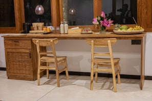 Una mesa de comedor de madera con dos sillas, una encimera de cocina y un ventanal con vistas.