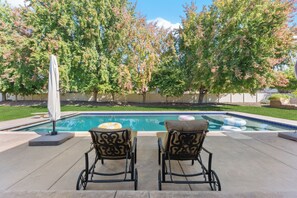 A swimming pool with two lounge chairs facing it, surrounded by trees and a fence. - 5-bdrm with hot tub, theater room & sports court in charming Eagle (Eagle)