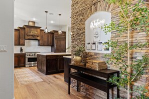 A modern kitchen with dark wood cabinets, a central island, and pendant lighting. - 5-bdrm with hot tub, theater room & sports court in charming Eagle (Eagle)