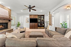 A spacious living room with a fireplace, a ceiling fan, and a built-in entertainment unit. - 5-bdrm with hot tub, theater room & sports court in charming Eagle (Eagle)