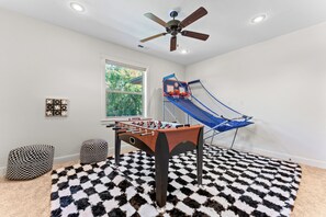 A room with a foosball table, a blue and red basketball hoop, and a ceiling fan. - 5-bdrm with hot tub, theater room & sports court in charming Eagle (Eagle)