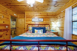Ein Zimmer in einer Holzhütte mit einem Bett, einem Schild mit der Aufschrift 'Lasst uns im Bett bleiben' und einem 'Happy'-Kissen.