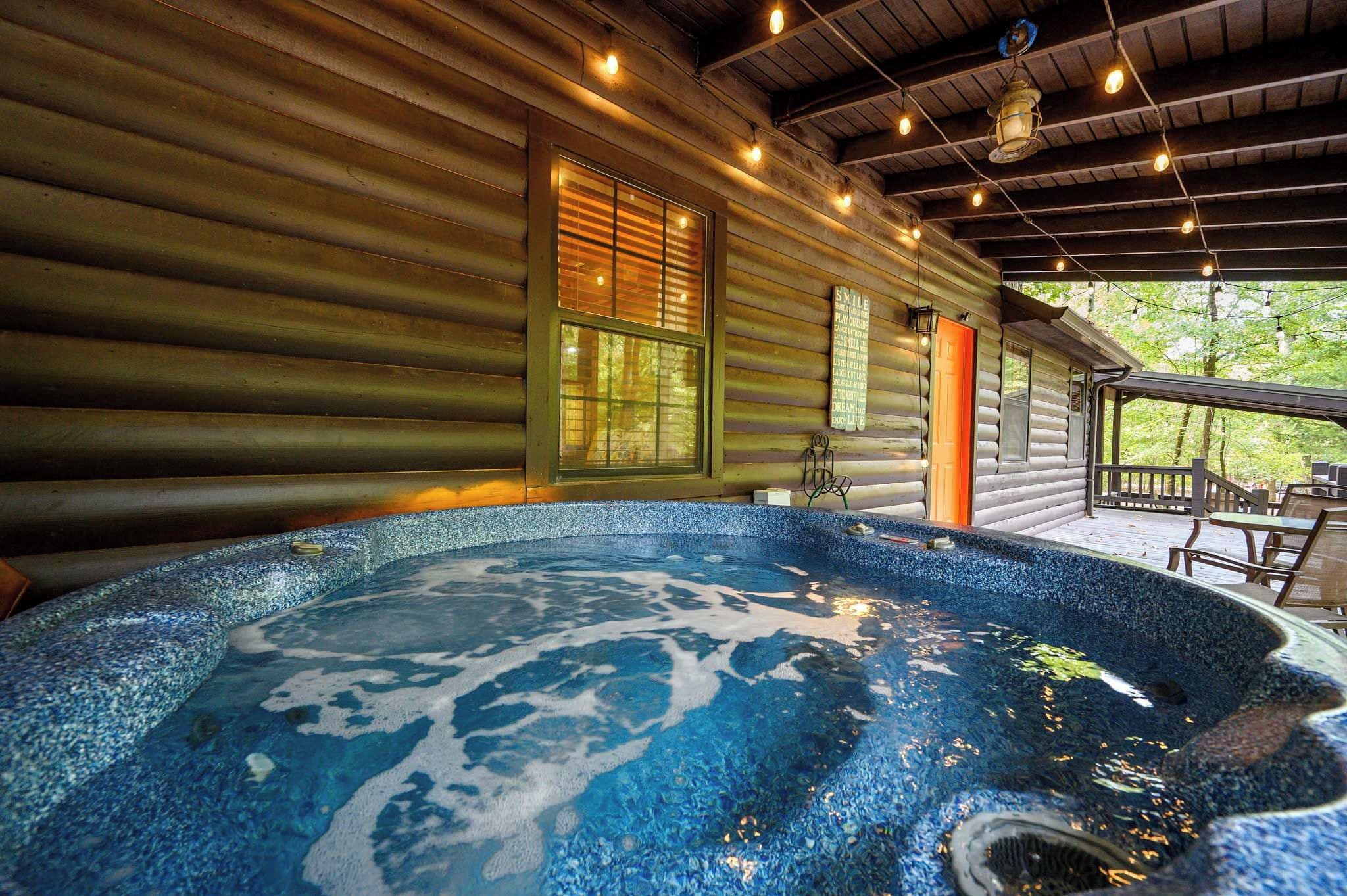 A hot tub with a wooden deck and a covered area with seating.