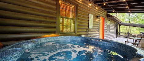A hot tub with a wooden deck and a covered area with seating.