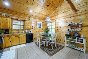 Ein Holzblockhaus-Interieur mit Küche, Essbereich und einer Kaffeestation.