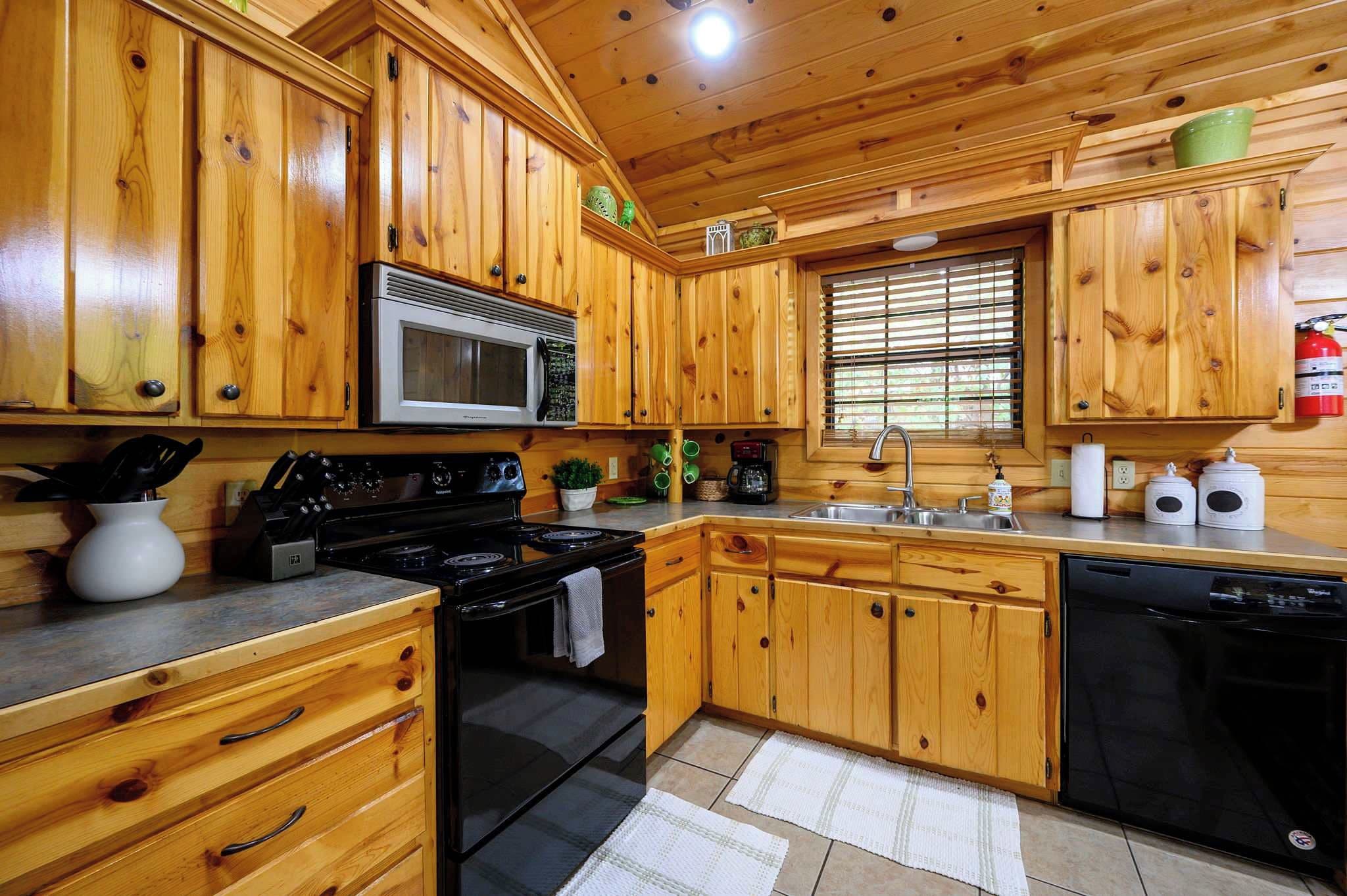 A kitchen with wooden cabinets, a microwave, stove, sink, and dishwasher.