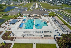 An aerial view of a residential area with a large swimming pool, multiple lounge areas, and a well-maintained lawn. - Relaxed 3-bedroom Villa with EV Charger - Bay Forest Community & Beach Shuttle (Ocean View)