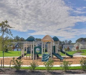 A playground with a climbing structure, slides, and a covered play area. - Relaxed 3-bedroom Villa with EV Charger - Bay Forest Community & Beach Shuttle (Ocean View)