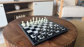 A chessboard on a round wooden table with a chair and a cabinet in the background.