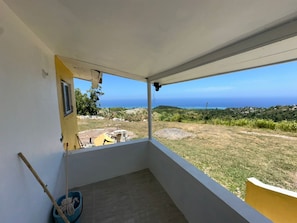 A balcony with a clear view of the ocean and a grassy landscape. - Spacious 1BR | Ocean Views & Mountain Escape (St. Ann Parish)