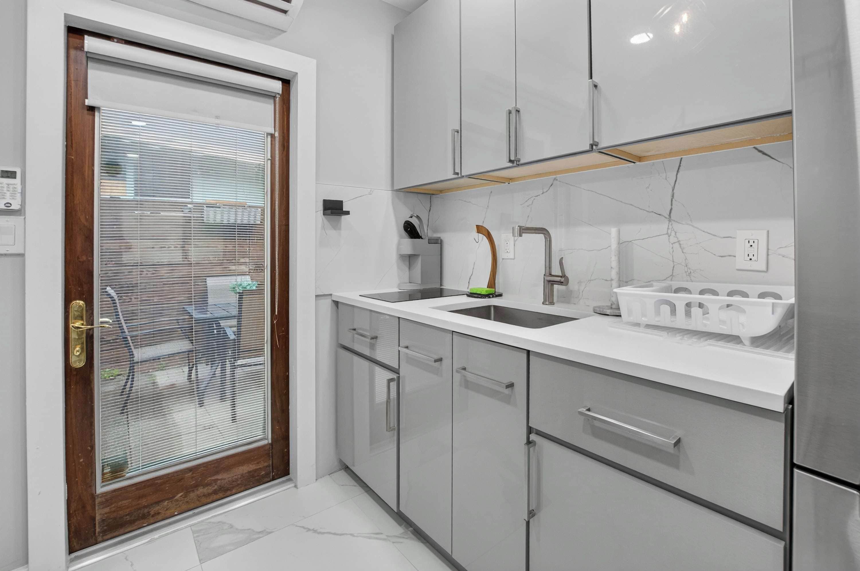 A modern kitchen with a white countertop, stainless steel appliances, and a wooden door with a glass panel.