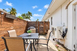 Un espacio al aire libre con mesa y sillas, una pequeña planta en maceta y una parrilla.