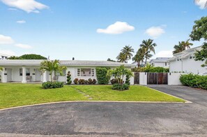 A residential area with white houses, a paved driveway, and a well-maintained lawn. - Marina Row 2 Coastal Studio (Delray Beach)
