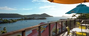 A balcony with a view of a body of water, a distant island, and a pier with boats. - Margaritaville Vacation Club - St. Thomas USVI Luxury Wyndham Studio Plus Suite (St Thomas)