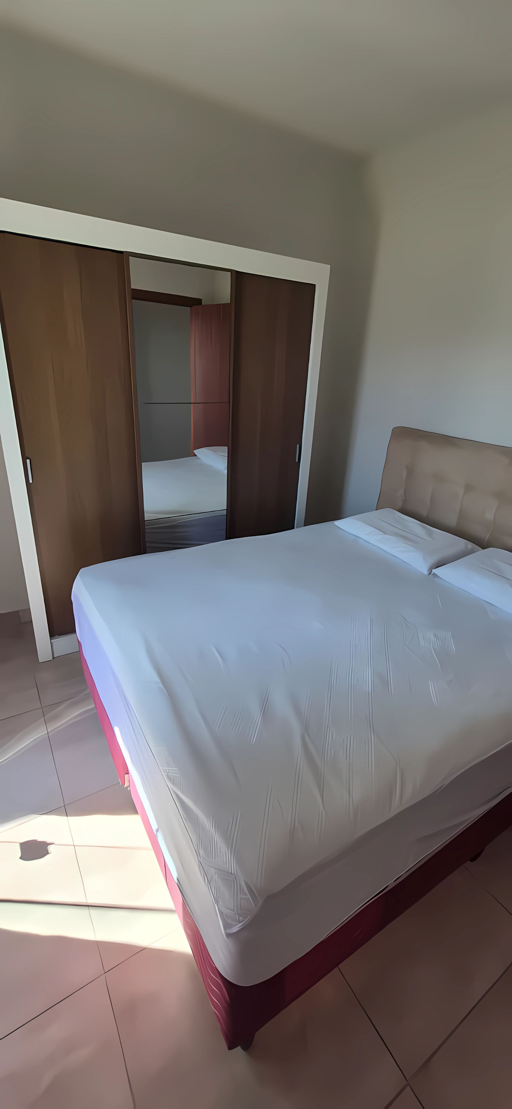 Ein Schlafzimmer mit einem Bett, einem Kleiderschrank und einem Spiegel.
