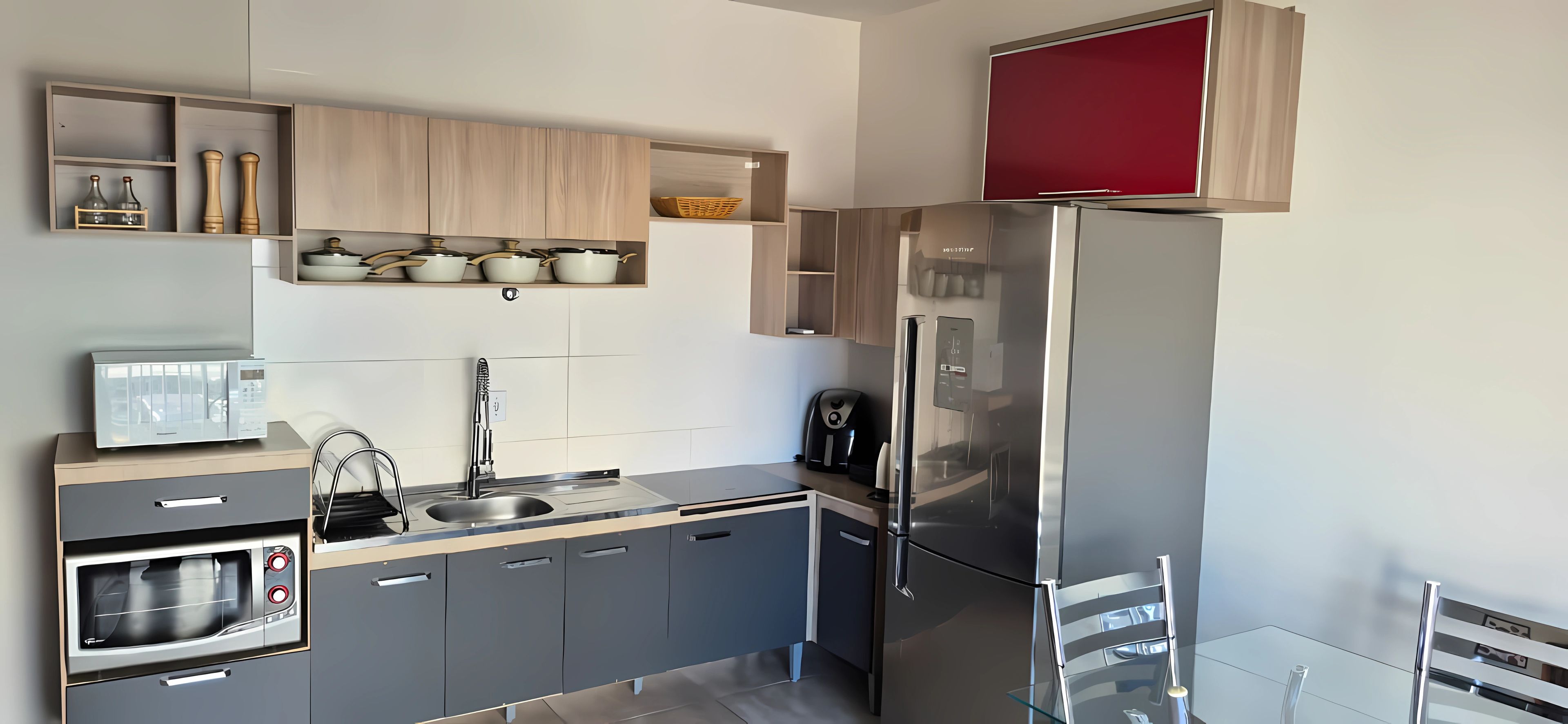 Eine moderne Küche mit grauen Schränken, einem Edelstahl-Kühlschrank, einem eingebauten Backofen und einer Kaffeemaschine.