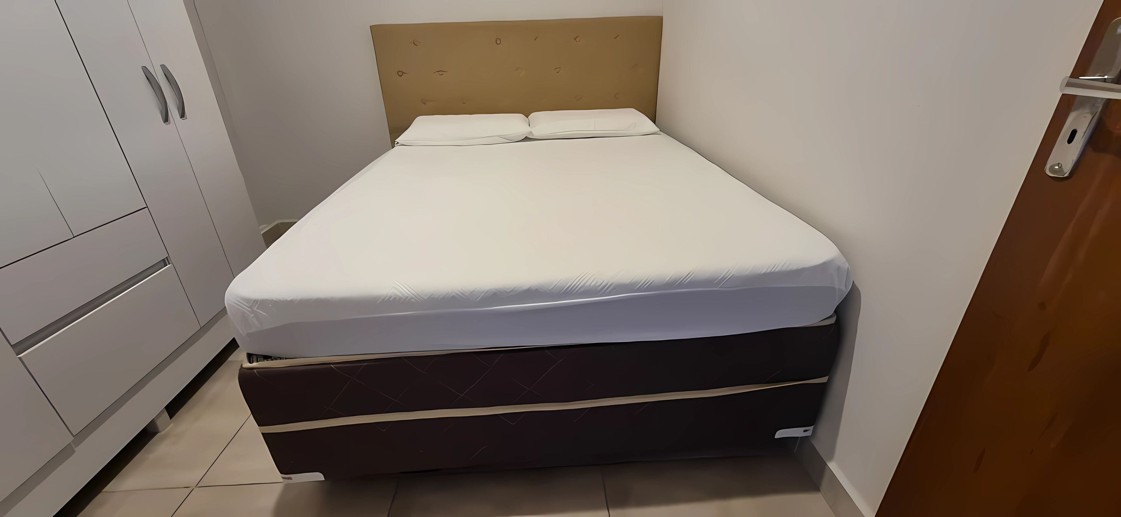 A single bed with a headboard, a wardrobe, and a door.
