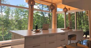 Une cuisine moderne dotée de grandes fenêtres, d’un ordinateur portable et d’un éclairage décoratif.