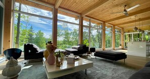 A spacious living area with large windows, a sofa, a coffee table, and a dining area. - The View. by Edelweiss ski hill. (Wakefield)