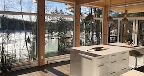 A modern kitchen with large windows, wooden beams, and a view of a snowy landscape. - The View. by Edelweiss ski hill. (Wakefield)
