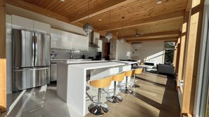A modern kitchen with stainless steel appliances, a central island with bar stools, and a wooden ceiling. - The View. by Edelweiss ski hill. (Wakefield)