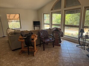 A living room with a large window, a sofa, a chair, and a small table.