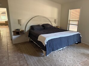 A bedroom with a bed, bedside tables, a rug, and a window with blinds. - Riverside Horse Ranch Unplugged (Thornton)