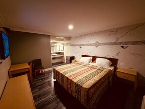 Una habitación de hotel con cama, escritorio, silla y una mesita.