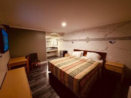 Una habitación de hotel con cama, escritorio, silla y una mesita.
