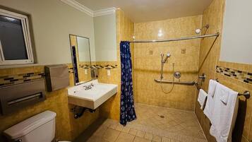 A bathroom with a toilet, sink, mirror, shower, and towel rack.