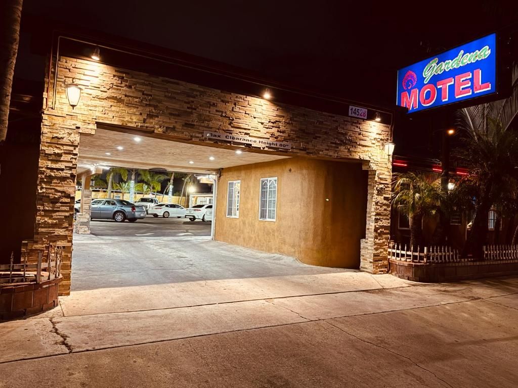 A motel with a stone facade, a neon sign, and a parking lot.