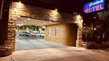 A motel with a stone facade, a neon sign, and a parking lot.