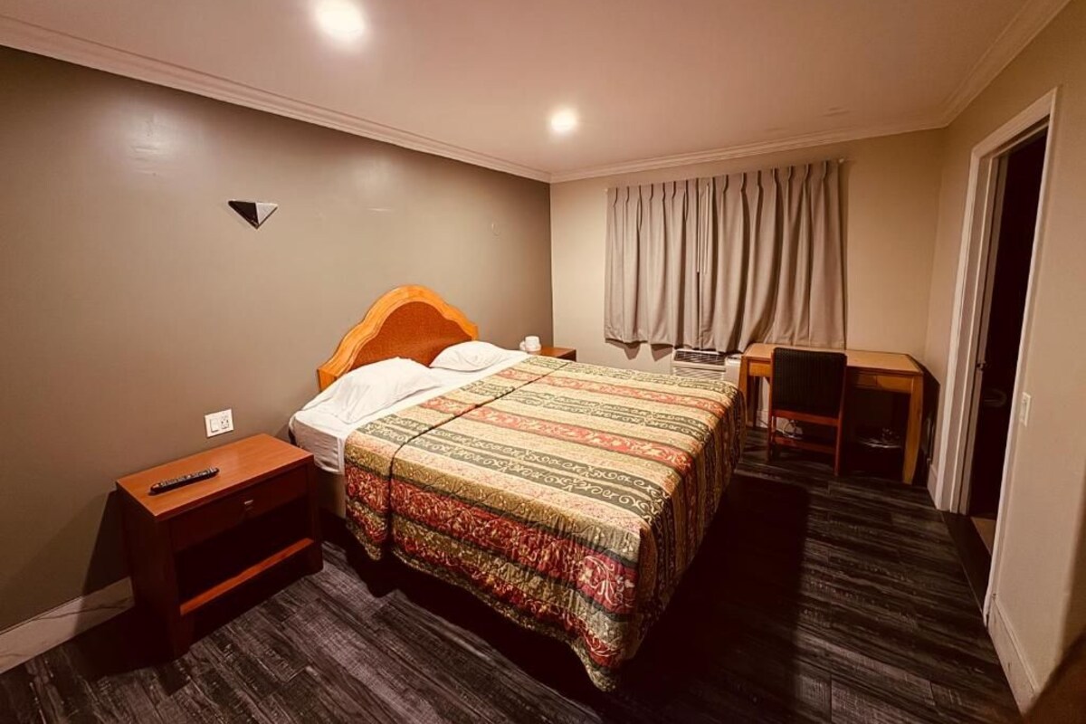 Una habitación de hotel con cama, mesita de noche, silla y escritorio con silla.