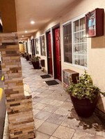 Un pasillo con puertas, plantas en macetas y piso de baldosas.