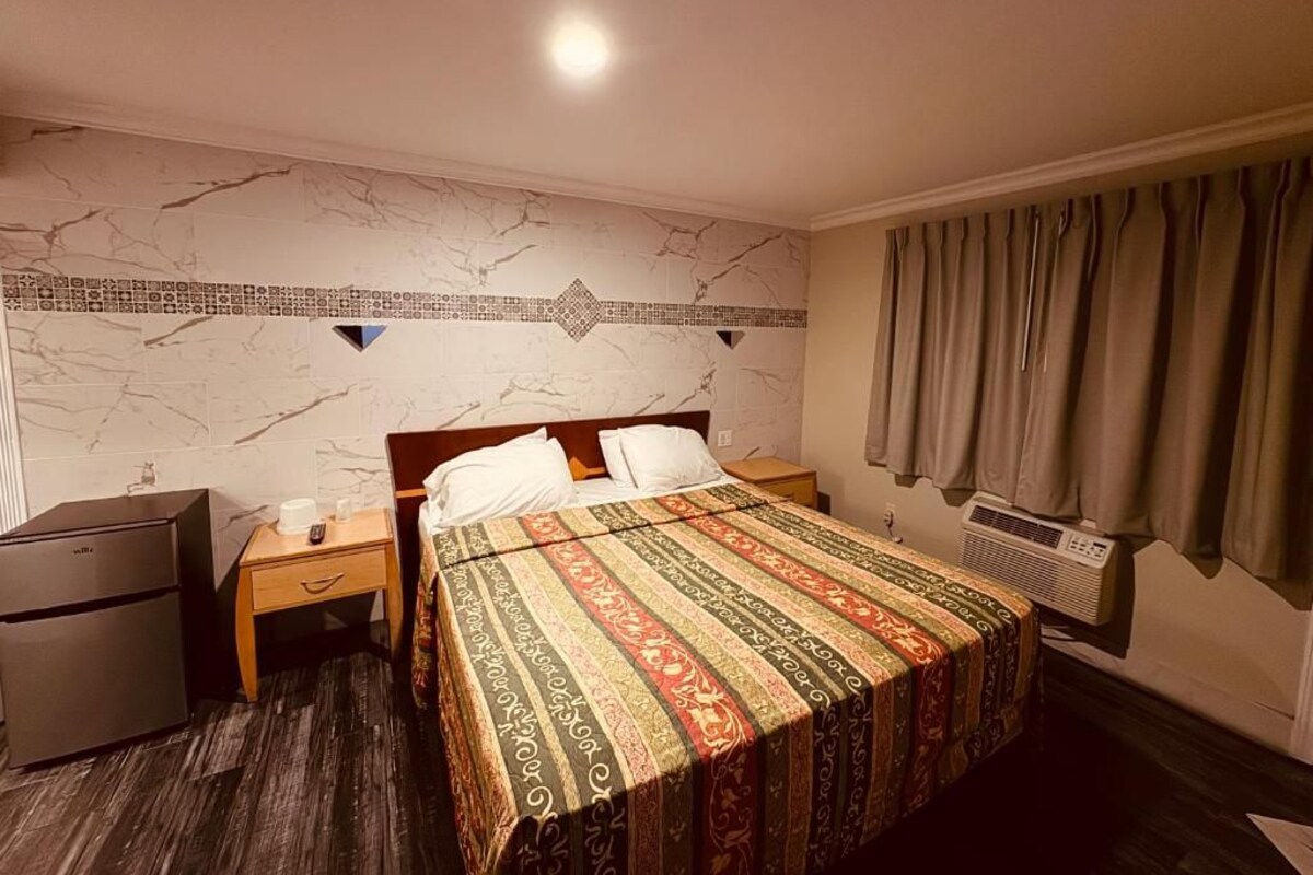 Una habitación de hotel con una cama, una mesita de noche, un calentador y un armario.