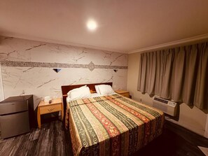 Una habitación de hotel con una cama, una mesita de noche, un calentador y un armario.