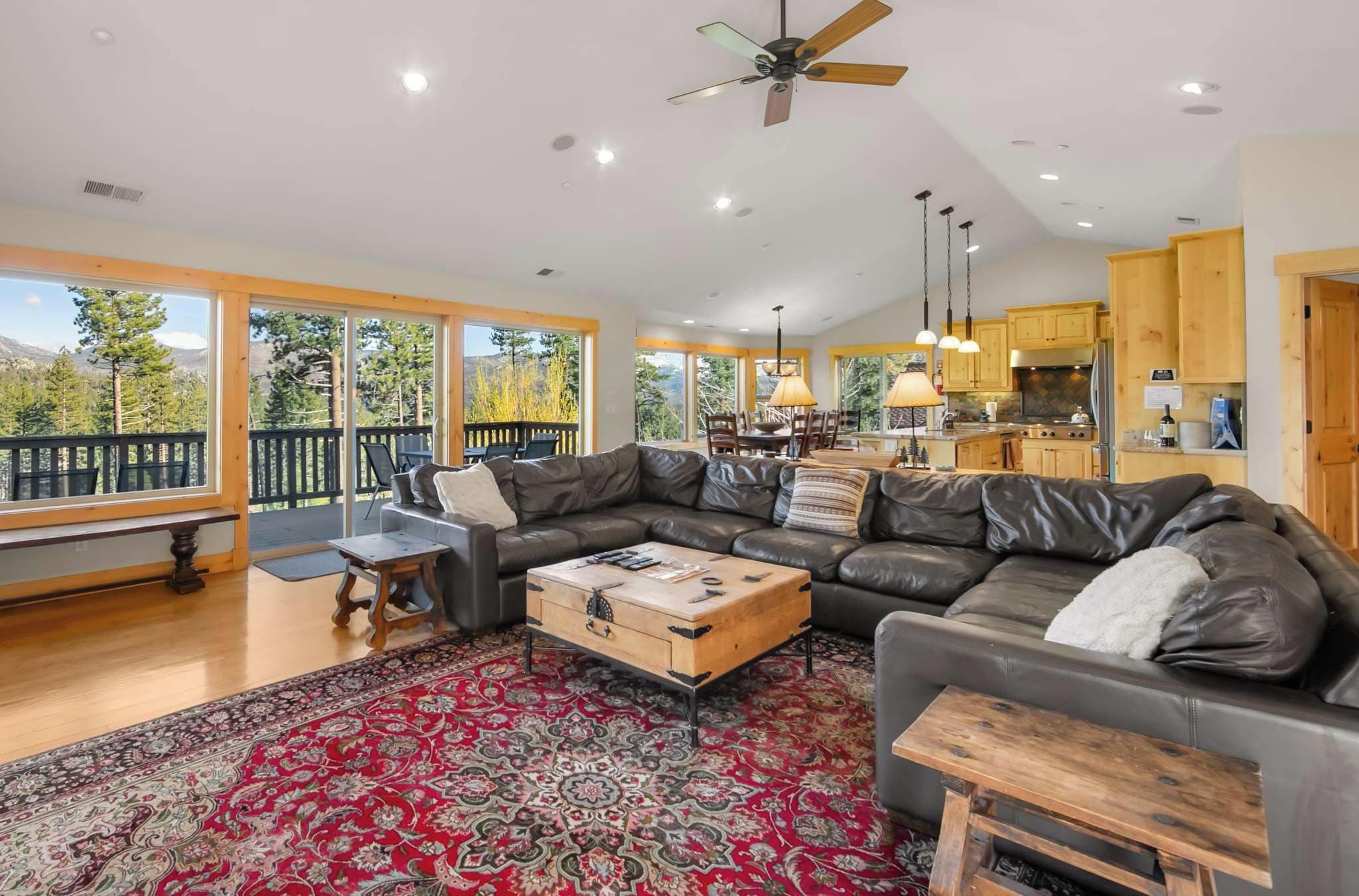 A spacious living area with a large leather sofa, a wooden coffee table, and a red patterned rug.