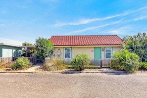 A single-story house with a red-tiled roof, a front porch, and a gravel driveway. - Siesta Villa | Private Patio | Dog Friendly (Port Aransas)