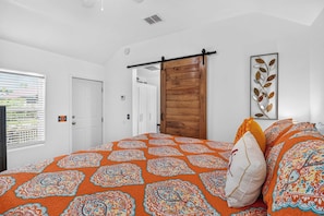 Un dormitorio con una cama grande, una puerta de madera y una ventana con persianas.