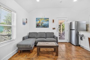 Ein modernes Wohnzimmer mit einem grauen Ecksofa, einem Holztisch und einem Gemälde eines Segelbootes an der Wand.