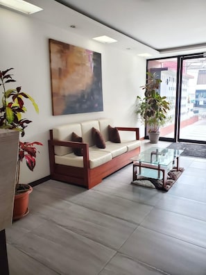 Interior moderno com sofá, mesa de centro de vidro e plantas em vasos.