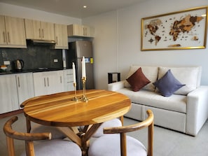 A modern kitchen with white cabinets, a stainless steel refrigerator, and a wooden dining table with two chairs. - QuitoVibes4U ¡Elegante, ubicación privilegiada, acogedor! (Quito)