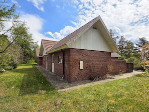 Ein eingeschossiges Backsteinhaus mit geneigtem Dach, einer kleinen angebauten Garage und einem gepflasterten Einfahrt.