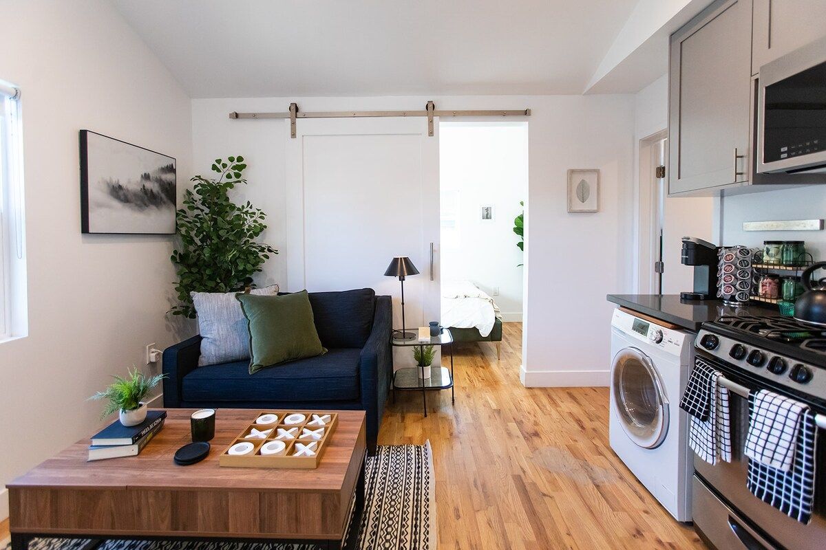 A compact living space with a sofa, coffee table, and a washing machine.