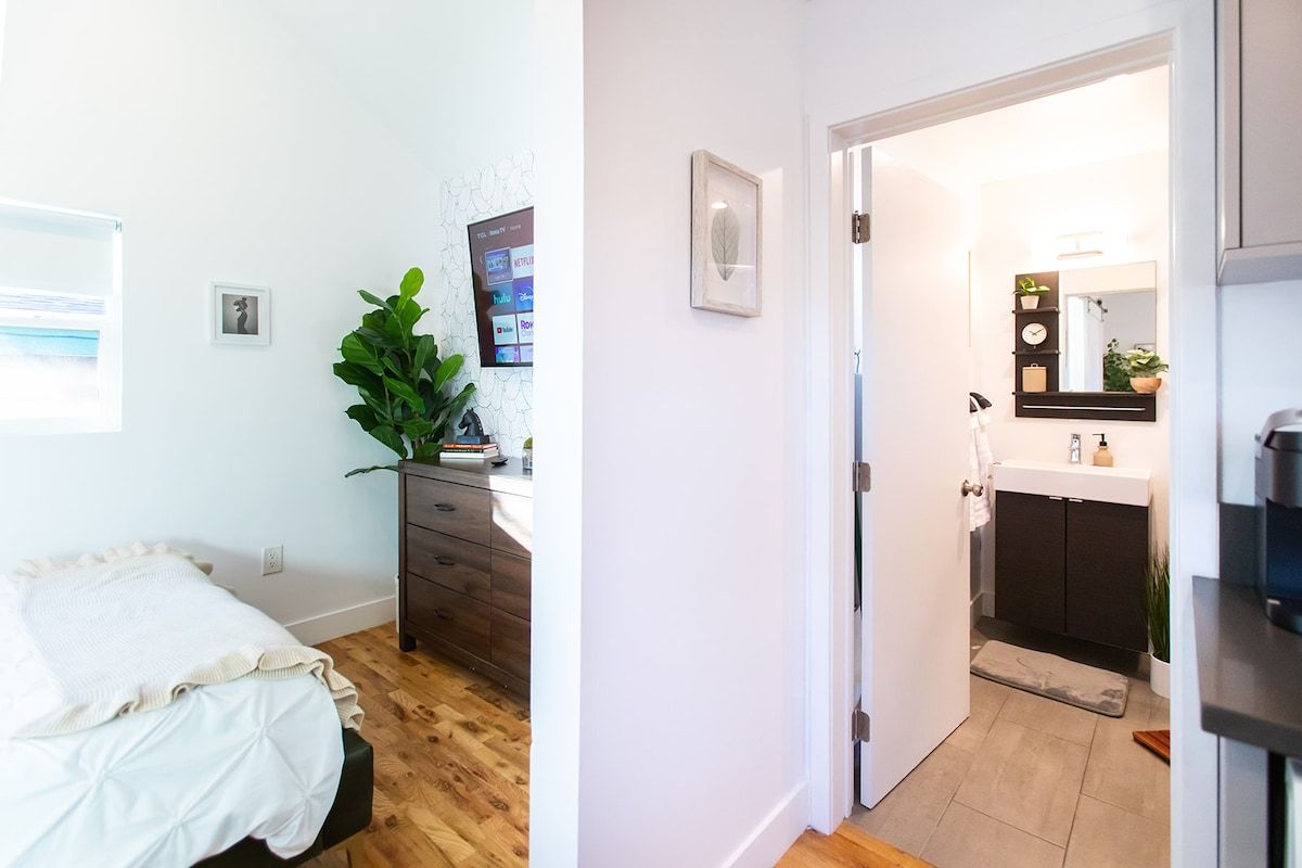 A bedroom with a bed, a dresser, and a plant.