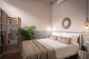 A bedroom with a bed, bedside lamps, a mirror, and a potted plant. - Ninemia Shore Retreat | Beachfront Escape with Hot Tub (Stalida)