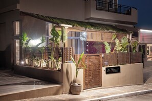 A modern building with a gated entrance, a sign for 'N Ninemia Shore Retreat,' and a well-maintained garden with various plants. - Ninemia Shore Retreat | Beachfront Escape with Hot Tub (Stalida)
